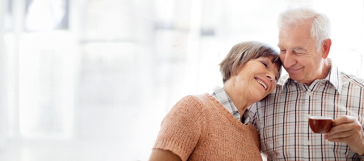 Glückliches Seniorenpaar dank passender Versicherung und niedrigen Beiträgen