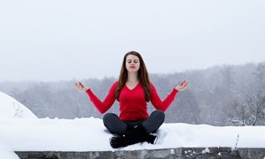 Frau im roten Pulli meditiert im Schnee